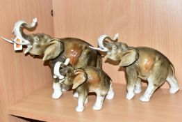 A SET OF THREE GRADUATING ROYAL DUX ELEPHANT FIGURES, modelled holding their trunks aloft, each with