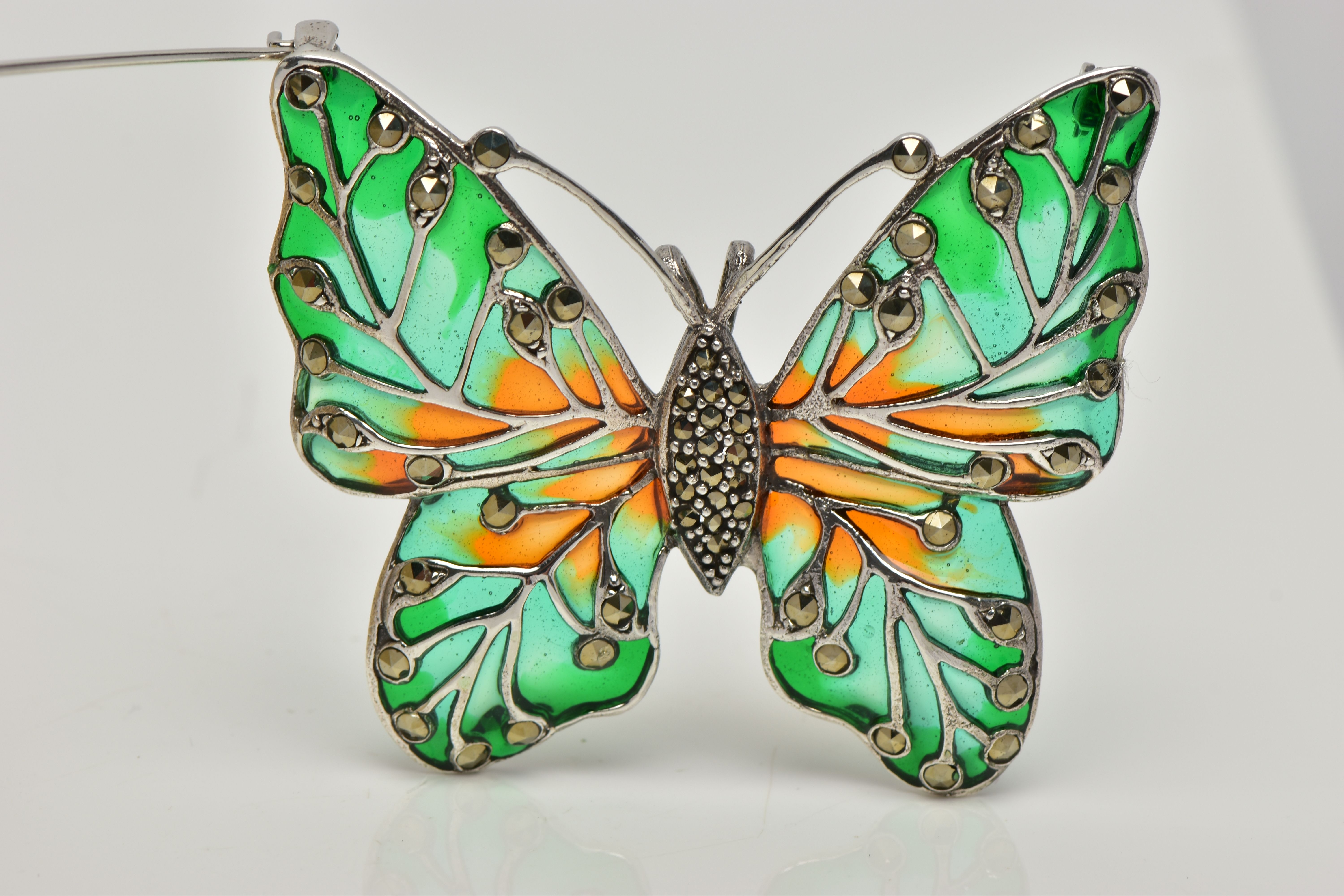 A WHITE METAL PLIQUE A JOUR BUTTERFLY BROOCH, the butterfly set with a marcasite body, enamelled