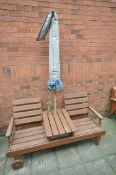 A PAINTED TEAK GARDEN BENCH with a central table, and wheels, length 168cm and a parasol (2)