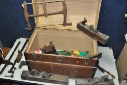 A VINTAGE TRUNK CONTAINING TOOLS to include three jack planes, plough plane, bow saw, T-square etc