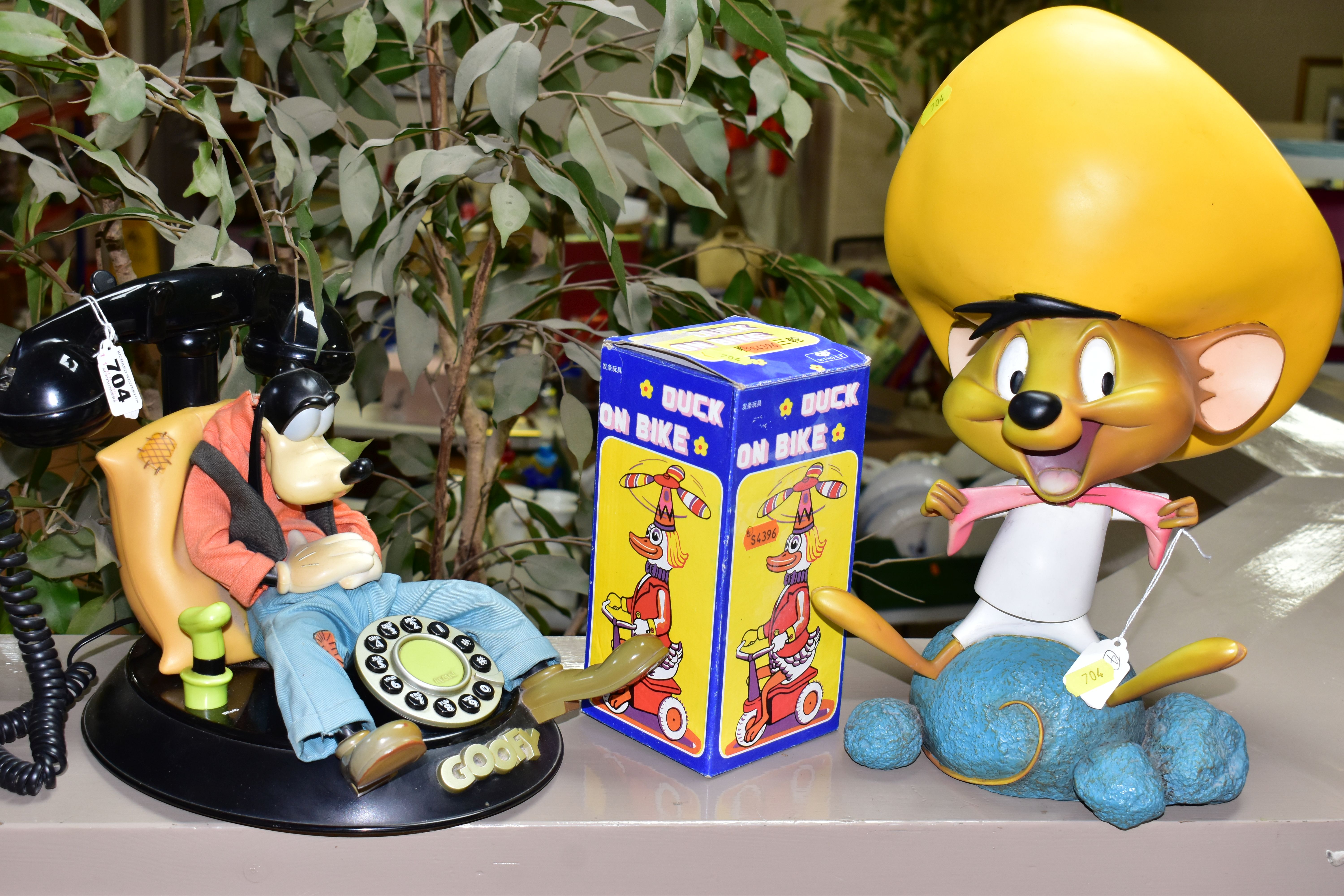 A WARNER BROS 'GOOFY' PUSH BUTTON PHONE (mybelle805), a wind up tin duck on a bike (boxed), also