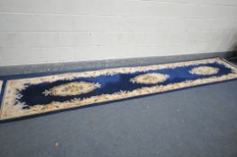 A WOOLLEN CHINESE CARPET RUNNER, with a dark blue field, 417cm x 77cm (condition:-some stains, see
