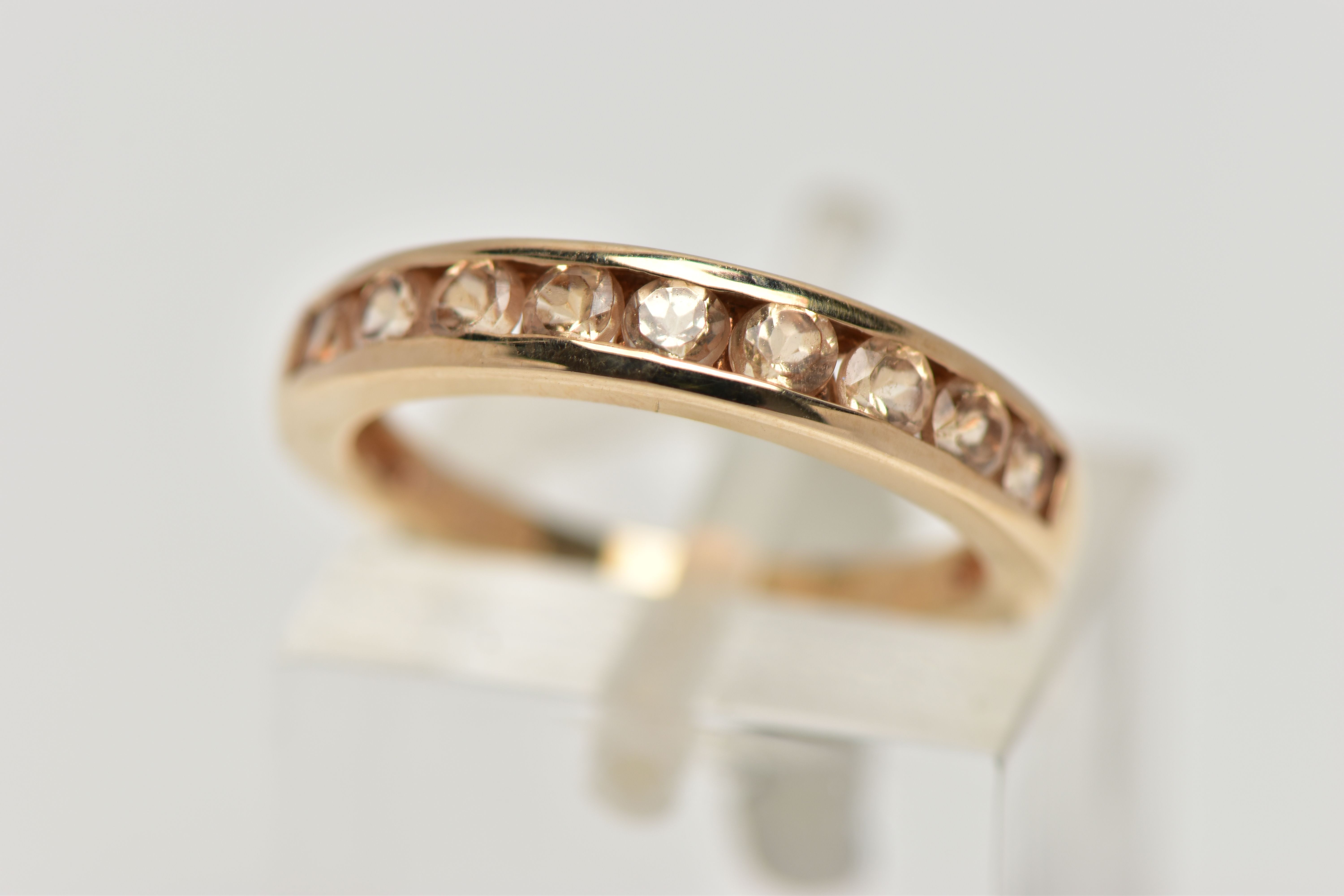 A 9CT GOLD GEM SET HALF ETERNITY RING, the circular shape peachy colour gems assessed as tourmaline,