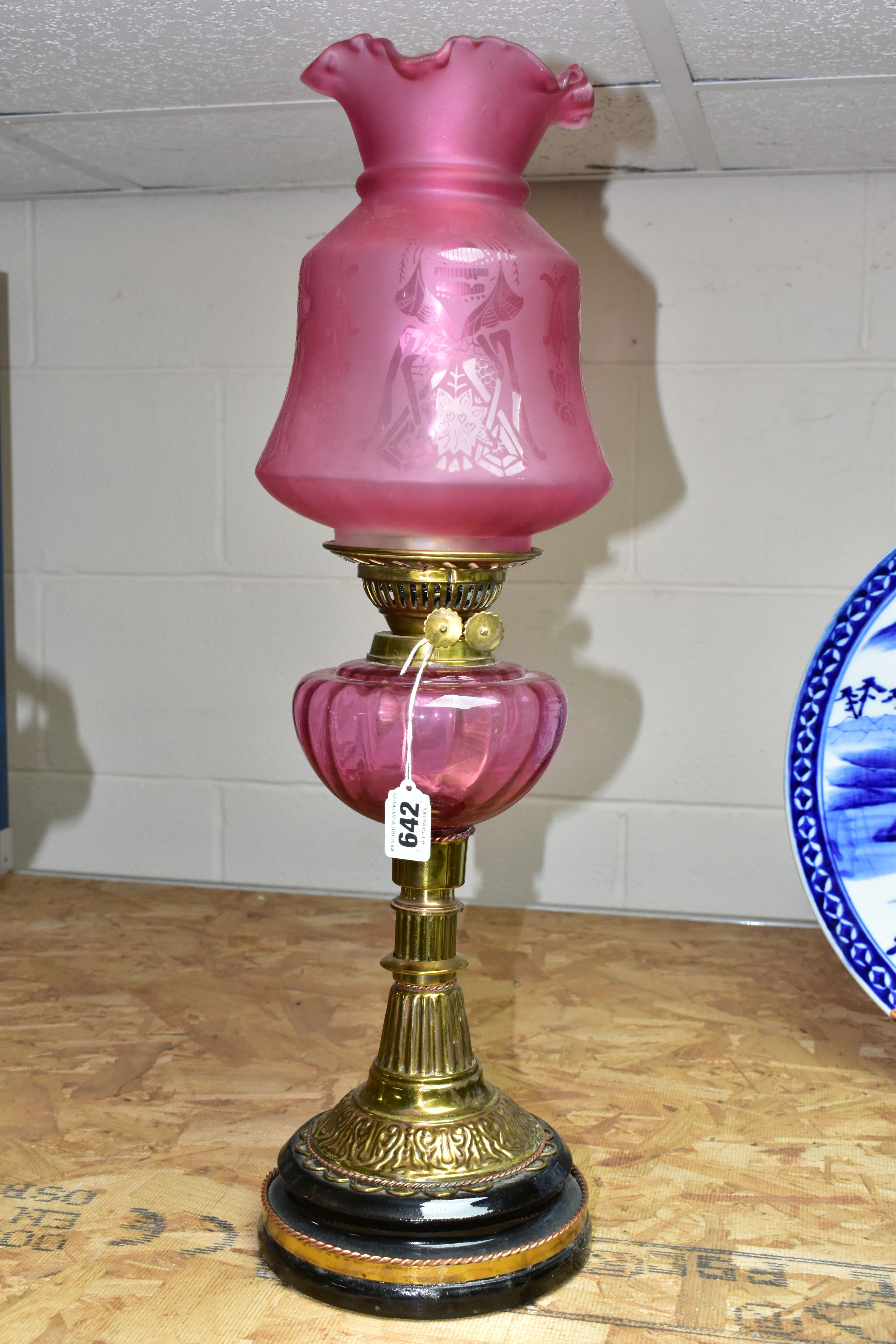 A LATE VICTORIAN BRASS BASED OIL LAMP, the domed acid etched clear and opaque cranberry shade