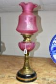 A LATE VICTORIAN BRASS BASED OIL LAMP, the domed acid etched clear and opaque cranberry shade