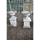 A PAIR OF COMPOSITE CAMPAGNA GARDEN URNS, of a shallow form, on a separate plinth, diameter 72cm x