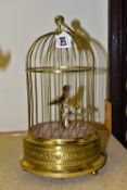 A REPRODUCTION AUTOMATON SINGING BIRD IN A BRASS CAGE, fitted with a hanging loop, embossed