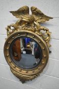 A REGENCY STYLE GILTWOOD CIRCULAR CONVEX WALL MIRROR, with a large bird surmount surrounded by