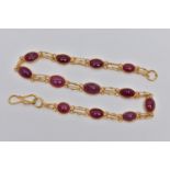 A YELLOW METAL AND RUBY SPECTACLE SET BRACELET, comprised of twelve slightly graduated oval cabochon