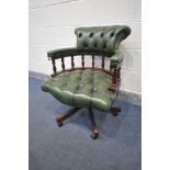 A MAHOGANY FRAMED BUTTONED GREEN LEATHER SWIVEL OFFICE CHAIR, with a scrolled back, on casters (