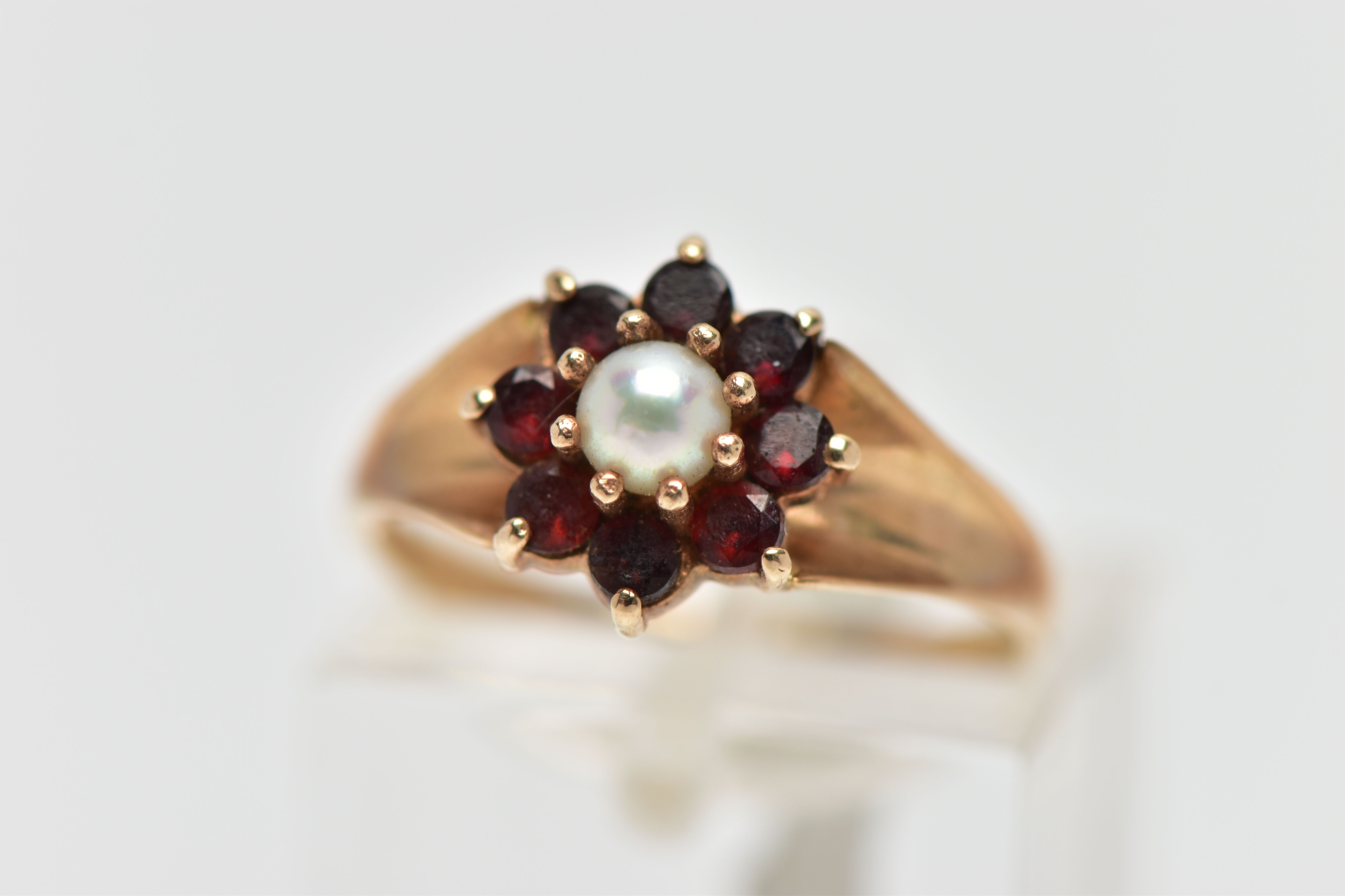 A 9CT GOLD CULTURED PEARL AND GARNET CLUSTER RING, the claw set cultured pearl, with circular cut
