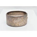 A WIDE SILVER HINGED BANGLE, with a scrolling foliate design, fitted with a push button integrated