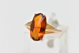 A YELLOW METAL PASTE SINGLE STONE RING, the fancy shape orange paste claw set, to the tapered