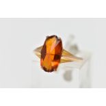 A YELLOW METAL PASTE SINGLE STONE RING, the fancy shape orange paste claw set, to the tapered