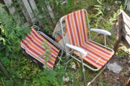A PAIR OF VINTAGE METAL FOLDING GARDEN CHAIRS with striped covering in a canvas cover and three more