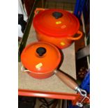 AN ORANGE LE CRUESET CASSEROLE AND SAUCEPAN, a circular covered casserole dish, diameter 23cm, a