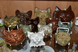 TWELVE STUDIO POTTERY CAT WALL MASKS, in a variety of coloured glazes, sizes and styles, all