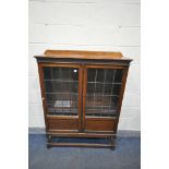 A 20TH CENTURY OAK LEAD GLAZED TWO DOOR BOOKCASE, with three adjustable shelves, on barley twist