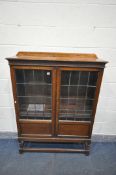 A 20TH CENTURY OAK LEAD GLAZED TWO DOOR BOOKCASE, with three adjustable shelves, on barley twist