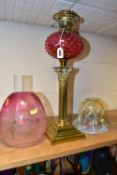 A LATE VICTORIAN OIL LAMP, the acid etched cranberry glass shade with broken section, cranberry