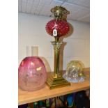 A LATE VICTORIAN OIL LAMP, the acid etched cranberry glass shade with broken section, cranberry