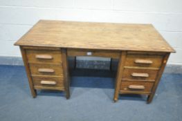 A 1940'S OAK DESK, with two brushing slides, and seven drawers, on casters, width 138cm x depth 67cm