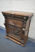 AN EARLY 20TH CENTURY FRENCH OAK SINGLE DOOR CABINET, carved with various masks that are flanking