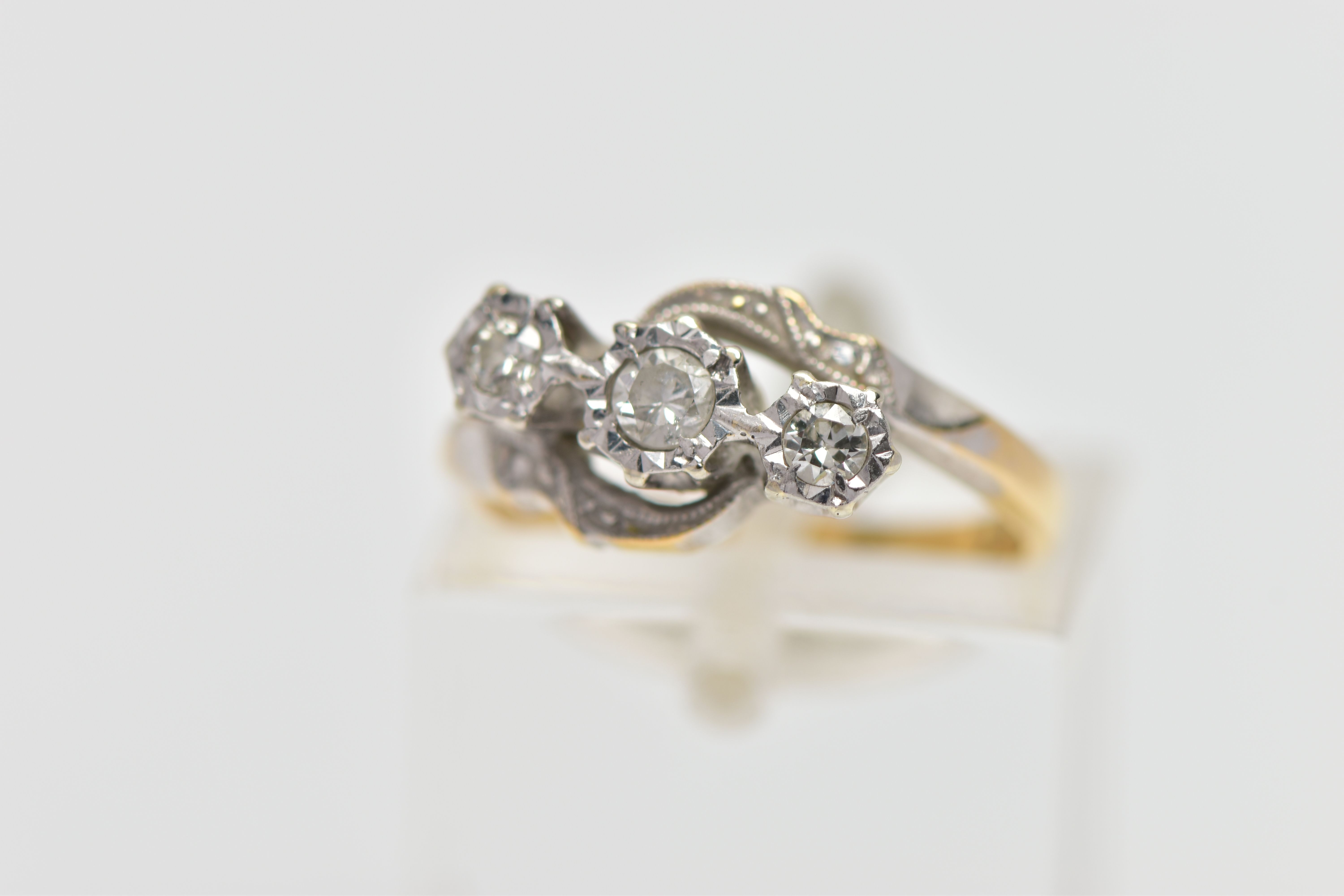 A YELLOW METAL THREE STONE DIAMOND RING, designed with three graduated, round brilliant cut