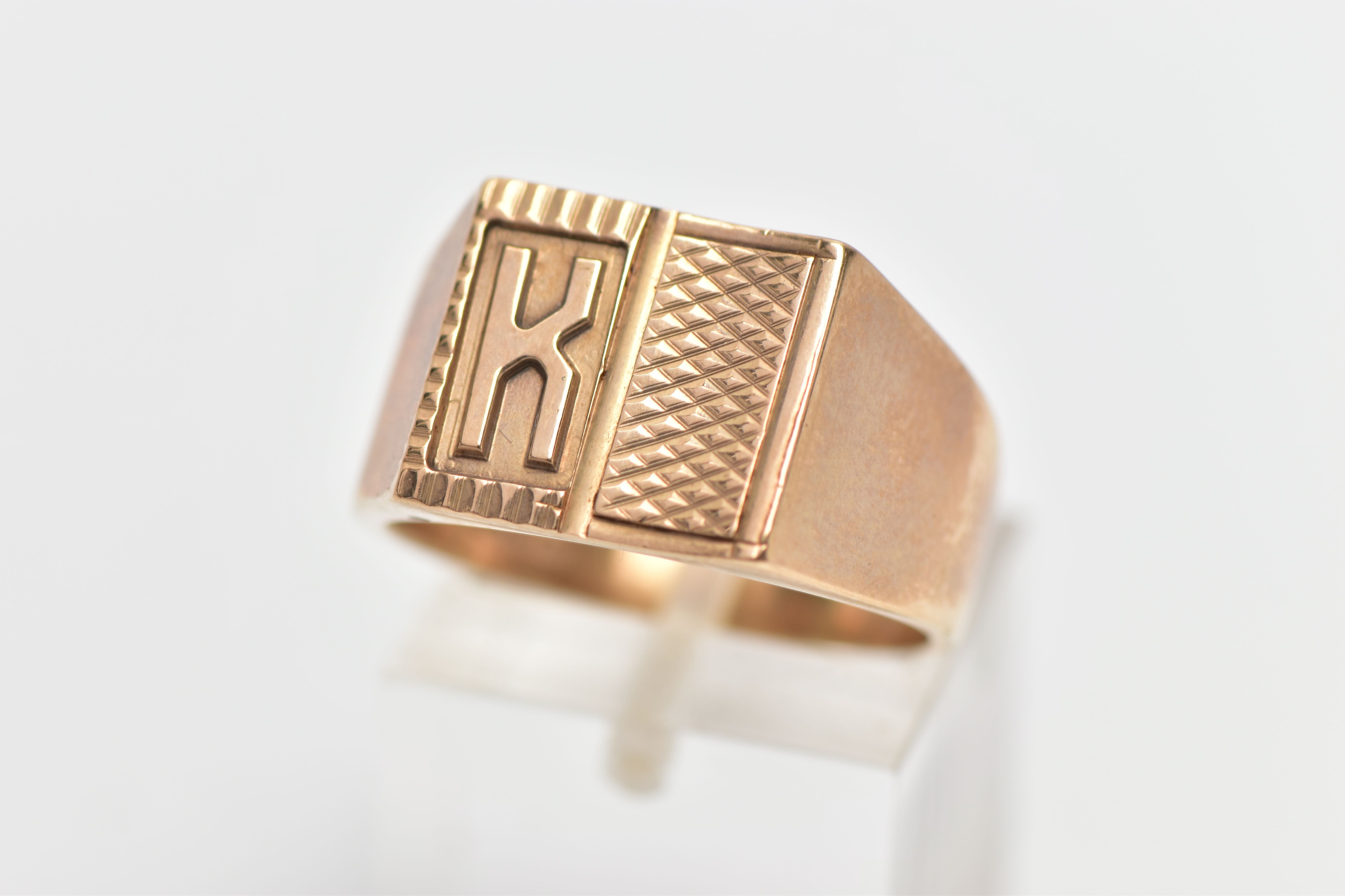 A 9CT YELLOW GOLD SIGNET RING, designed as an engine turned panel with the letter 'K', to the