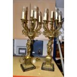 A PAIR OF TORCHIERE STYLE TABLE LAMPS, six brass candle holders on each, held aloft by classical