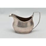 A GEORGIAN SILVER MILK JUG, with engraved foliate design and undulating pattern oval base, with