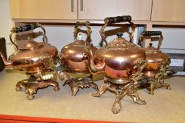 FOUR COPPER SPIRIT KETTLES, comprising Victorian copper kettles on ornate brass stands, three