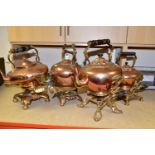 FOUR COPPER SPIRIT KETTLES, comprising Victorian copper kettles on ornate brass stands, three