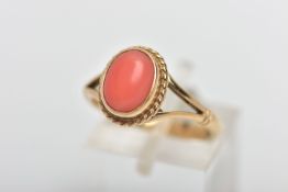 A 9CT GOLD CORAL DRESS RING, the oval coral cabochon, within a rope twist collet surround, measuring