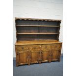 A REPRODUCTION OAK DRESSER, with a two tier plate rack, four drawers, and four panelled cupboard