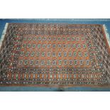 A 20TH CENTURY TEKKE ORANGE GROUND RUG, with a multi strap border, and twenty six medallions,