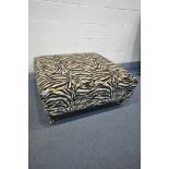 A SQUARE ZEBRA PRINT UPHOLSTERED FOOSTOOL, on turned legs and brass casters, 104cm squared x