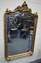 A LARGE GILT RESIN BEVELLED EDGE FRENCH WALL MIRROR, the top with foliate carving and detailing (