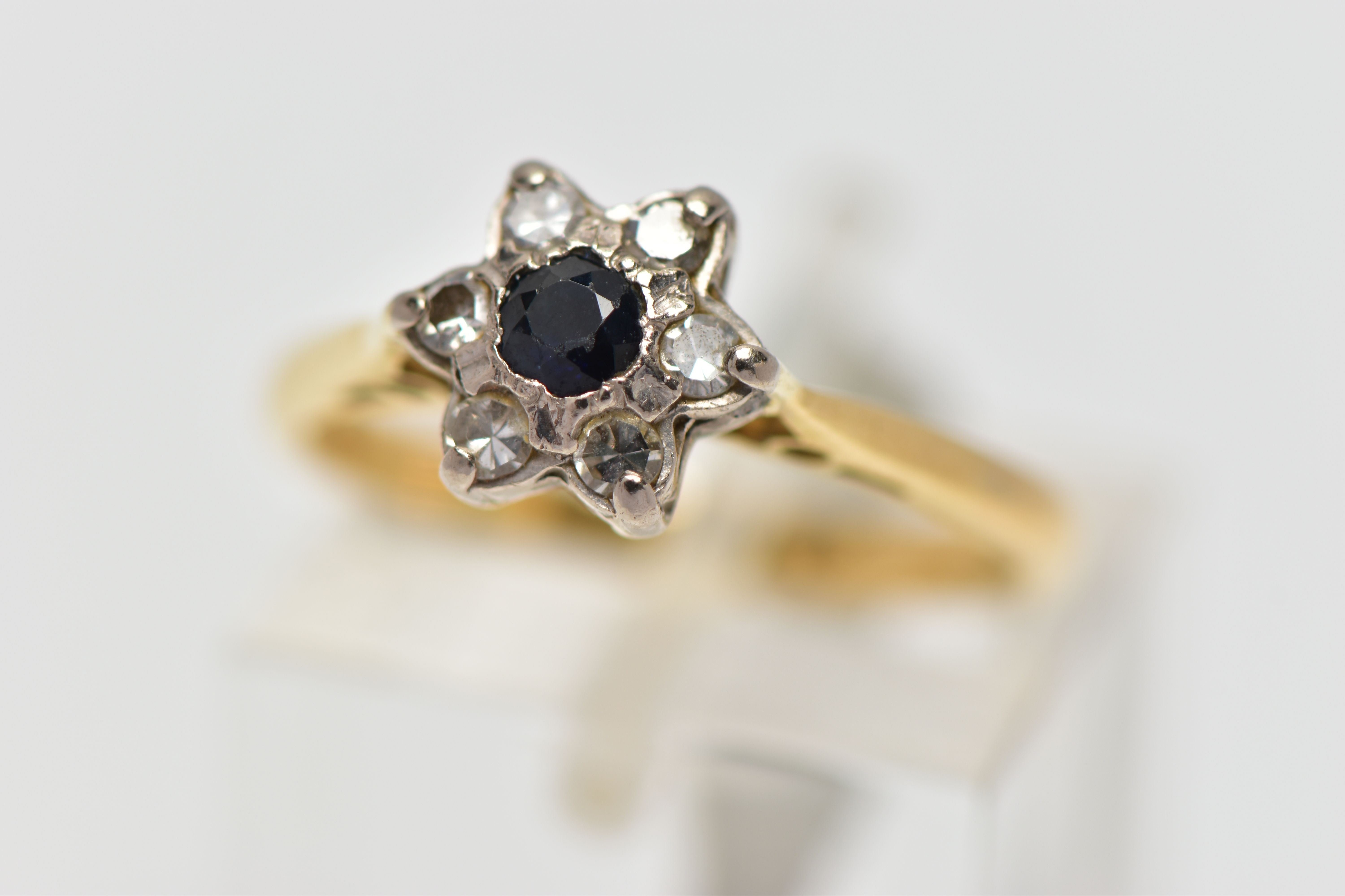 A YELLOW AND WHITE METAL CLUSTER RING, a circular cut sapphire and six single cut diamonds prong set