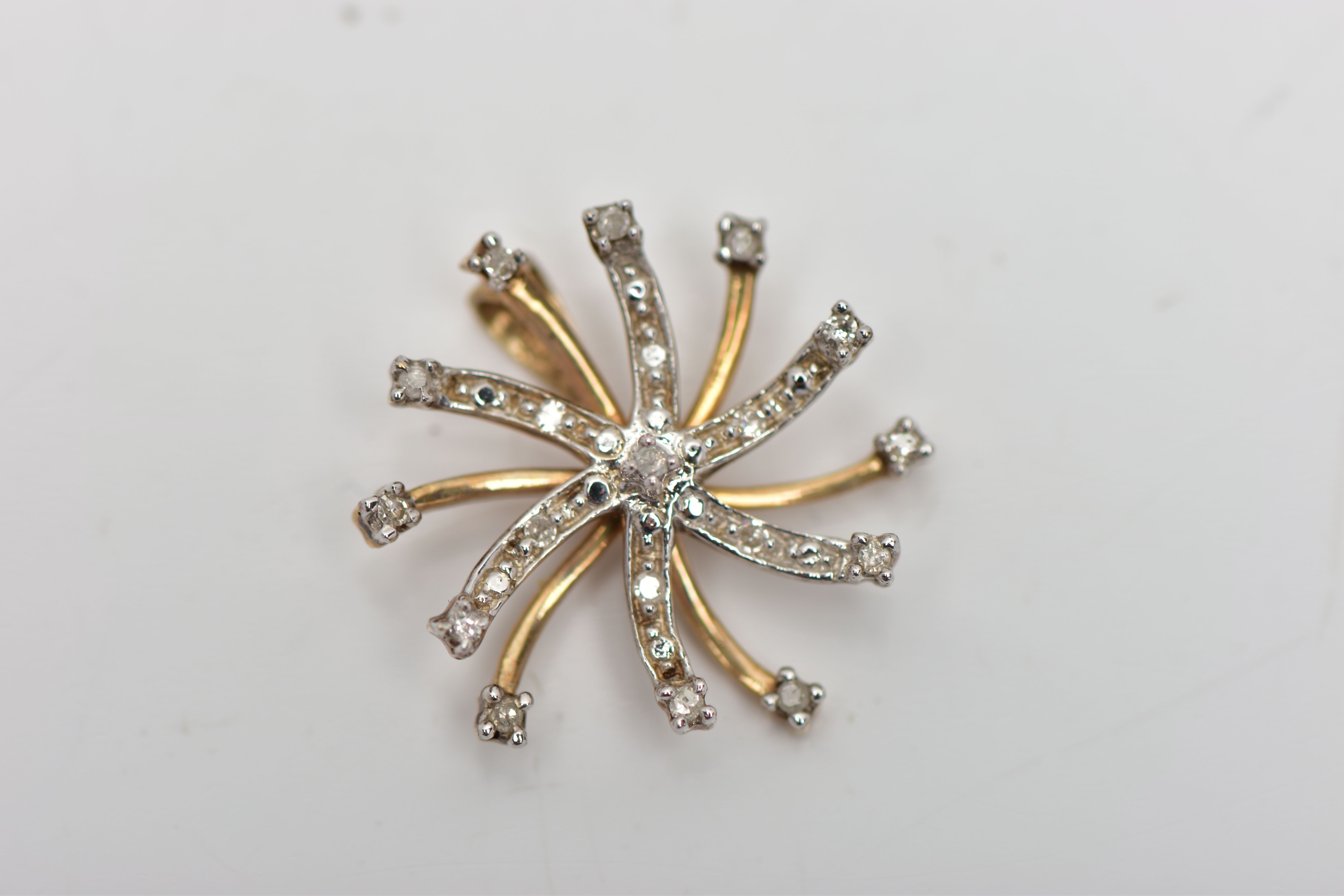 A 9CT GOLD DIAMOND SWIRL PENDANT, of scrolling design, the single cut diamond spray, with