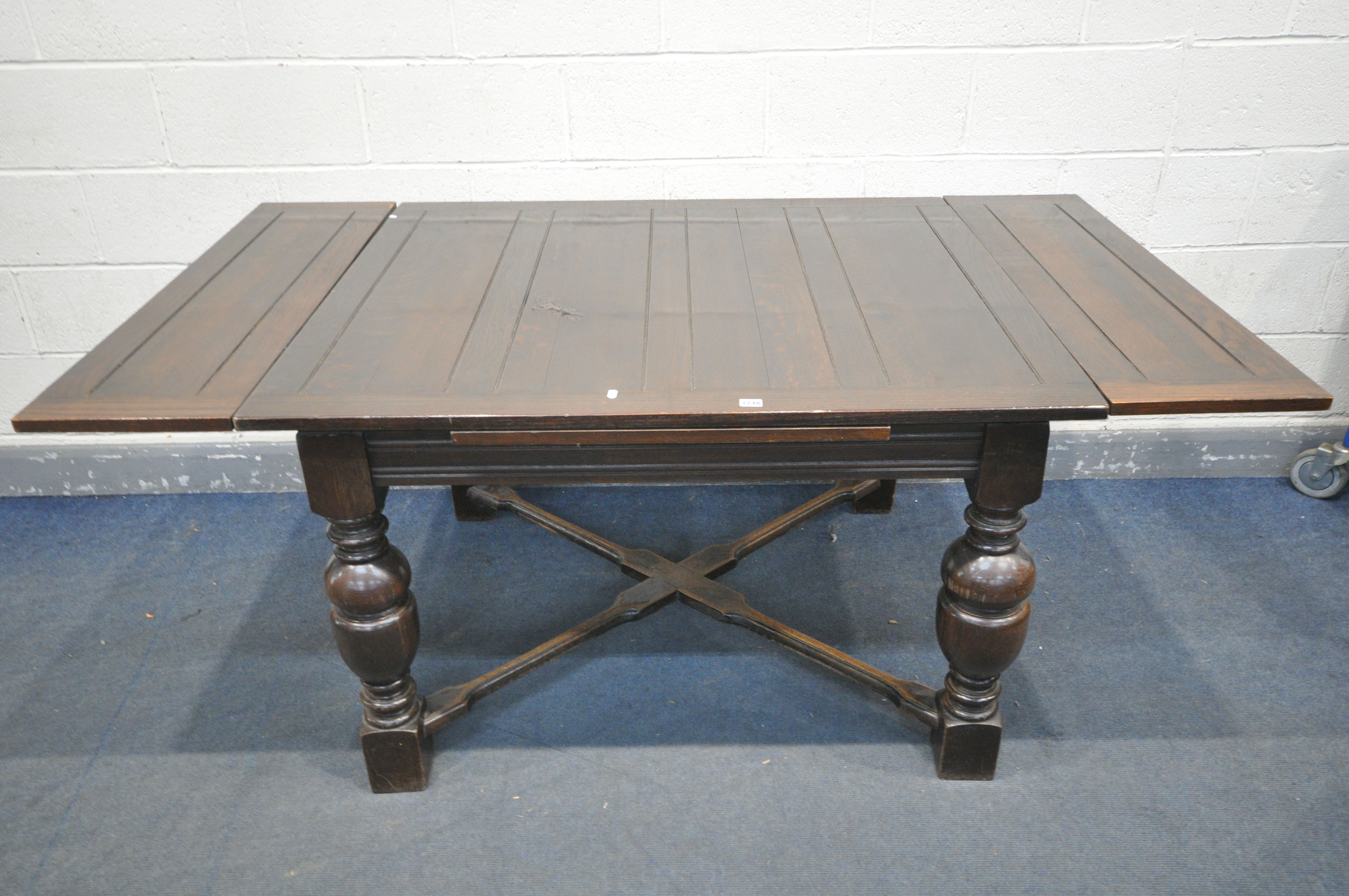 AN EARLY 20TH OAK DRAW LEAD DINING TABLE, on bulbous legs, united by a cross stretcher, open