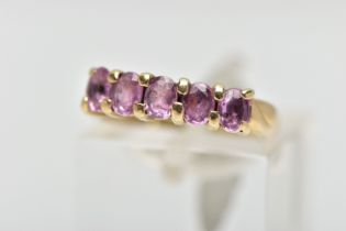 A 9CT GOLD FIVE STONE RING, designed with a row of four claw set, oval cut pink stones assessed as