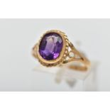 A 9CT GOLD AMETHYST SINGLE STONE RING, the oval cut amethyst collet set, within a rope twist