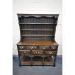 A REPRODUCTION OAK DRESSER, with a three tier plate rack, above a base with seven assorted