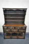 A REPRODUCTION OAK DRESSER, with a three tier plate rack, above a base with seven assorted