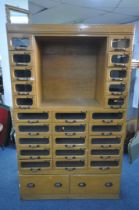 A MID-CENTURY BEECH HABERDASHERY CABINET, made up of two banks of five glass front drawers that's