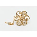 A YELLOW METAL SPLIT PEARL FLORAL BROOCH, of scrolling design, the central split pearl with six