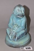 A BESWICK MONKEY FIGURE, number 397, seated on a circular pottery base, holding a piece of fruit,