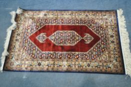 A SILK EFFECT PERSIAN RUG, with a red and blue field, 110cm x 67cm
