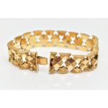 A YELLOW METAL FANCY LINK BRACELET, a wide bracelet made up of star shape links with floral